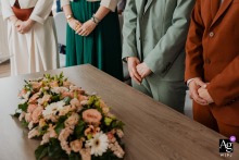At the City Hall of Pierric near Nantes, France, the hands of the couple and witnesses are arranged in the same position around a central floral decoration, creating an unusual detail image with a mood that feels closer to a funeral than a wedding.