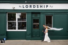 Outside The Lordship Pub in Dulwich, London, England, the bride and groom walk together in front of the venue, creating a relaxed and natural wedding-day portrait.