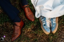 At Riverlands Wedding Barn in East Riding of Yorkshire, United Kingdom, the groom’s formal shoes rest beside the bride’s blue trainers, creating a playful detail that reflects their personalities and wedding-day style.