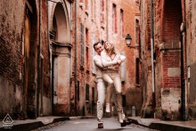 Her fiancé is lifting her back up by surprise during engagement photoshoot in downtown Toulouse France