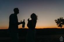 A couple enjoys aperitifs, silhouetted against a sunset in Bannay, creating a warm and intimate engagement scene.