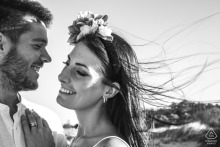A couple embraces on Ravenna Wild Beach, Italy, as the wind playfully tousles their hair under a clear sky.