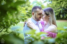 A couple poses for an intimate portrait, framed by vibrant flowers, at Normafa, surrounded by lush, picturesque scenery.