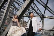 Engaged couple poses on the Bund, Shanghai, against a steel bridge blending romance with urban sophistication.
