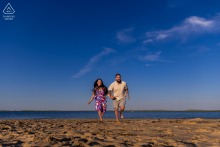 A couple runs hand in hand on Chatham Lighthouse Beach, Massachusetts, joyously celebrating their love on a sunny day.
