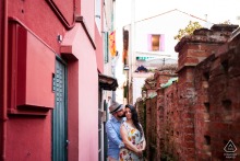Couple hugging closely in a narrow, charming street of Caorle, Venice, Italy, surrounded by historic colorful buildings.