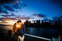 A couple kisses at Brooklyn Bridge Park, sun shining behind them, during their New York engagement session.