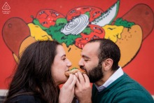 Couple shares a hotdog outside Victory Grill in Chicago’s Logan Square during their engagement session.