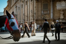 The couple share an intense kiss amid bustling Quattro Canti, historic center, Palermo, Sicily.