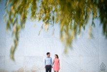 Engaged couple joyfully poses together outside Kennedy Center, Washington DC, with modern architecture shining brightly.