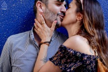 A couple shares an intimate kiss while standing against a striking blue wall in Paris, France.