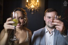 Engaged couple raises glasses, each covering one eye, in Whiskey Bar and Grill, Cleveland.