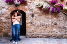 Couple poses in Grado’s historic village, standing together before a beautiful textured stone wall.