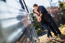 Engaged couple in San Jose, CA poses by trailer; groom-to-be kisses bride-to-be’s cheek affectionately.