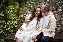 Groom to be kisses bride to be's temple on a bench in Verulamium Park, Hertfordshire.