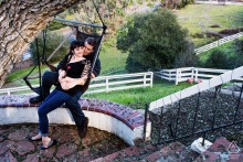 San Jose, CA — A couple sits cozily together in a hanging chair suspended from a tree, creating a relaxed and intimate engagement portrait in a natural setting.