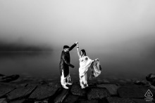 A couple dances together at Lake Louise in Canada on a foggy morning. The black and white photograph captures their graceful movement and intimacy, with misty lake scenery providing a romantic backdrop.