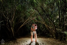 An engaged couple is captured in a tender, face-to-face embrace in Bedmar, Jaén. The surrounding archway of trees frames the pair, highlighting the photographer's backlighting.