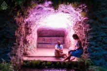 A tranquil pre-wedding portrait of a couple in Spain, sheltered within a stone cave. The soft, radiant pink glow casts a distinctive hue over the rock formations, emphasizing their calm and intimate connection.