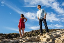 An image capturing a couple's quiet contemplation on the Northern California coast. They are seen standing apart on the rocks, each looking away in a reflective pose, suggesting a shared, unspoken connection.