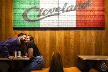 At Geraci's Slice Pizza in Cleveland, OH, the couple enjoys a few slices together beneath the bold 'Cleveland' wall art displayed prominently overhead in their favorite pizza shop.