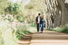 Along the Canal du Midi in Toulouse, France, the couple walks closely together on a sun-dappled trail beneath the trees, enjoying a peaceful promenade.