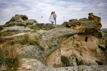 In Göreme, Nevşehir, Turkey, a Cappadocia pre-wedding photo captures the couple perched atop ancient cave dwellings, surrounded by the breathtaking landscape of the Old World.