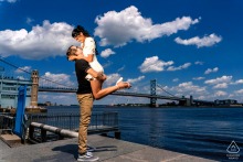 In Philadelphia, Pennsylvania, he lifts her joyfully under the bright blue sky, both framed by the bridge and the sparkling waters below.