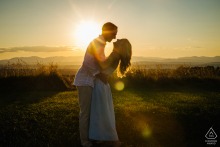 Engagement Portrait of a Couple Laughing at Sunset in Rhinebeck In Rhinebeck, NY, the couple stands face to face at a lookout, sharing laughter as the sunset glows warmly behind them.