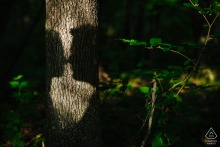 Engagement Portrait of a Couple’s Kissing Shadows on a Tree in Rhinebeck In Rhinebeck, NY, the shadows of the couple’s kissing profiles are cast onto a tree trunk, blending beautifully with the forest surroundings.