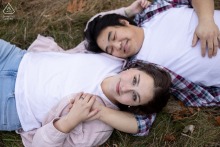At Vaughn Woods in Hallowell, Maine, a couple lies on their backs in the grass with their heads positioned in opposite directions for a yin-yang style portrait.