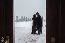Engaged couple gazes into each other's eyes at Kondiaronk Belvedere, Montreal, set against a dreamy backdrop of a snow-covered, foggy cityscape stretching out in the distance.