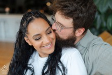 Couple in Portland, Maine during their engagement session, with him behind her, kissing her cheek as they share a smile, radiating joy and affection.