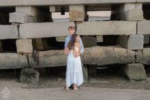 A couple hugs during their engagement session beside Harpswell’s iconic Cribstone Bridge in Maine, the unique granite slab foundation resembling stacked Lego blocks in this memorable coastal setting.
