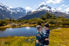 Couple cuddles together to stay warm on Key Summit, Routeburn Track, New Zealand, their affection and adventure reflected in the stunning mountain landscape during their journey.