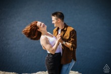 Couple joyfully swings each other around in the Catskills, New York, with hair flying in the wind, capturing a playful and energetic engagement portrait amidst natural, scenic beauty.