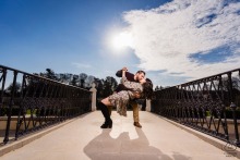 He gently dips her on a bridge at Longwood Gardens in Philadelphia as they share a kiss, with open skies and bright afternoon light adding warmth to this affectionate and fun portrait.