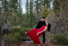He dips her gracefully in South Lake Tahoe, her red dress contrasting with his black attire, creating an elegant and formal engagement portrait set against a scenic natural backdrop.