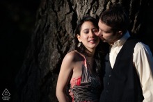 The couple shares an intimate embrace by a rock wall in San Francisco, California, softly lit to highlight their closeness in this warm and heartfelt engagement portrait.