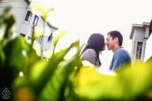 The couple stands nose to nose in San Francisco, surrounded by lush foliage in the soft-focus foreground, highlighting their connection in this intimate engagement portrait.