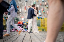 An engaged couple steals a kiss in front of a rustic wooden buoy display while urban street life passes by in Portland, Maine.