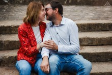 An engaged couple leans toward each other while taking a breather on stone stairs in Metz, France.