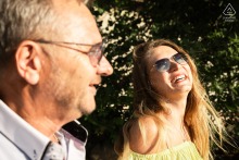 Engaged woman laughs in the warm sunlight beside her partner during a portrait session at Château des Allinges in Haute-Savoie, France.