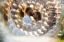 Couple stands close together amid sparkling reflections and warm lights during an artistic engagement portrait at Camp North End in Charlotte, North Carolina.