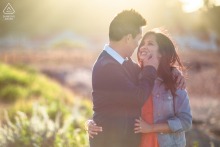 An engaged couple stands close and smiles during an outdoor pre-wedding session in a scenic area of San Francisco, California.