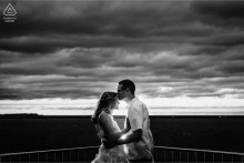 The engaged couple shares a romantic kiss at Milton Olive Park in Chicago, Illinois, as dramatic clouds gather over the vast waters of Lake Michigan during their outdoor portrait session.
