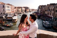 This happy couple shares a joyful smile together while standing on the top of the iconic Rialto Bridge in Venice, Italy, celebrating their engagement in a truly timeless city.