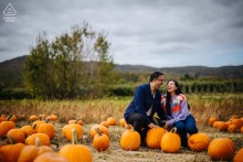 Amidst a pumpkin field in Fishkill, NY, a couple shares a lighthearted engagement portrait, the autumn setting and vibrant pumpkin colors providing a perfect backdrop to their joyful connection.