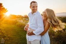 In Rhinebeck, NY, a couple swings together at sunset, their engagement portrait framed by warm golden light, the open field and glowing sky enhancing the romantic atmosphere.