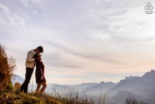 At the end of a day in Grenoble, France, a couple enjoys a candid pose as soft evening light highlights their connection, framed by the warmth and charm of the surrounding mountains.